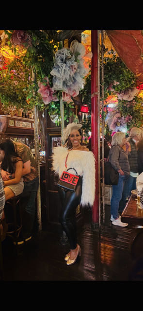 Afternoon tea outfit in NYC featuring white feather top, fascinator hat and statement handbag at a themed bar