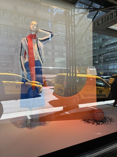 Bloomingdale’s window display featuring a mannequin in a striped cardigan and red scarf alongside a basketball during the New York Knicks celebration in Manhattan.