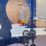 Bloomingdale’s NYC window display celebrating the New York Knicks championship with “GO NY GO” artwork, yellow taxis, and Manhattan street reflections.