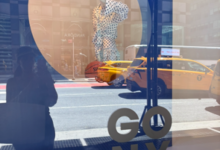 Bloomingdale’s NYC window display celebrating the New York Knicks championship with “GO NY GO” artwork, yellow taxis, and Manhattan street reflections.