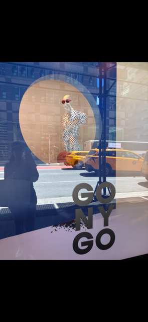 Bloomingdale’s NYC window display celebrating the New York Knicks championship with “GO NY GO” artwork, yellow taxis, and Manhattan street reflections.