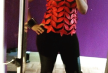 Full-length mirror photo featuring a bold red and black textured top paired with black pants and coordinating red high heels.